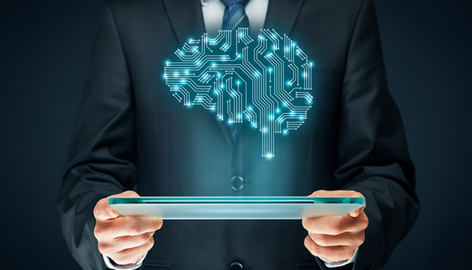 A man in a suit stands and holds a tablet with a digital brain hovering above.